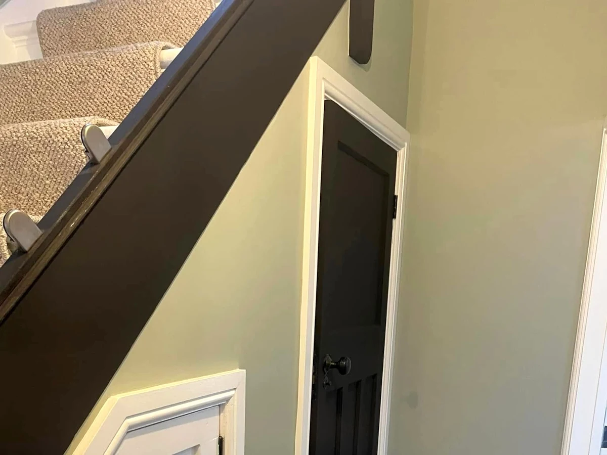 Repainted stairwell with black handrail, decorators covering Pennard