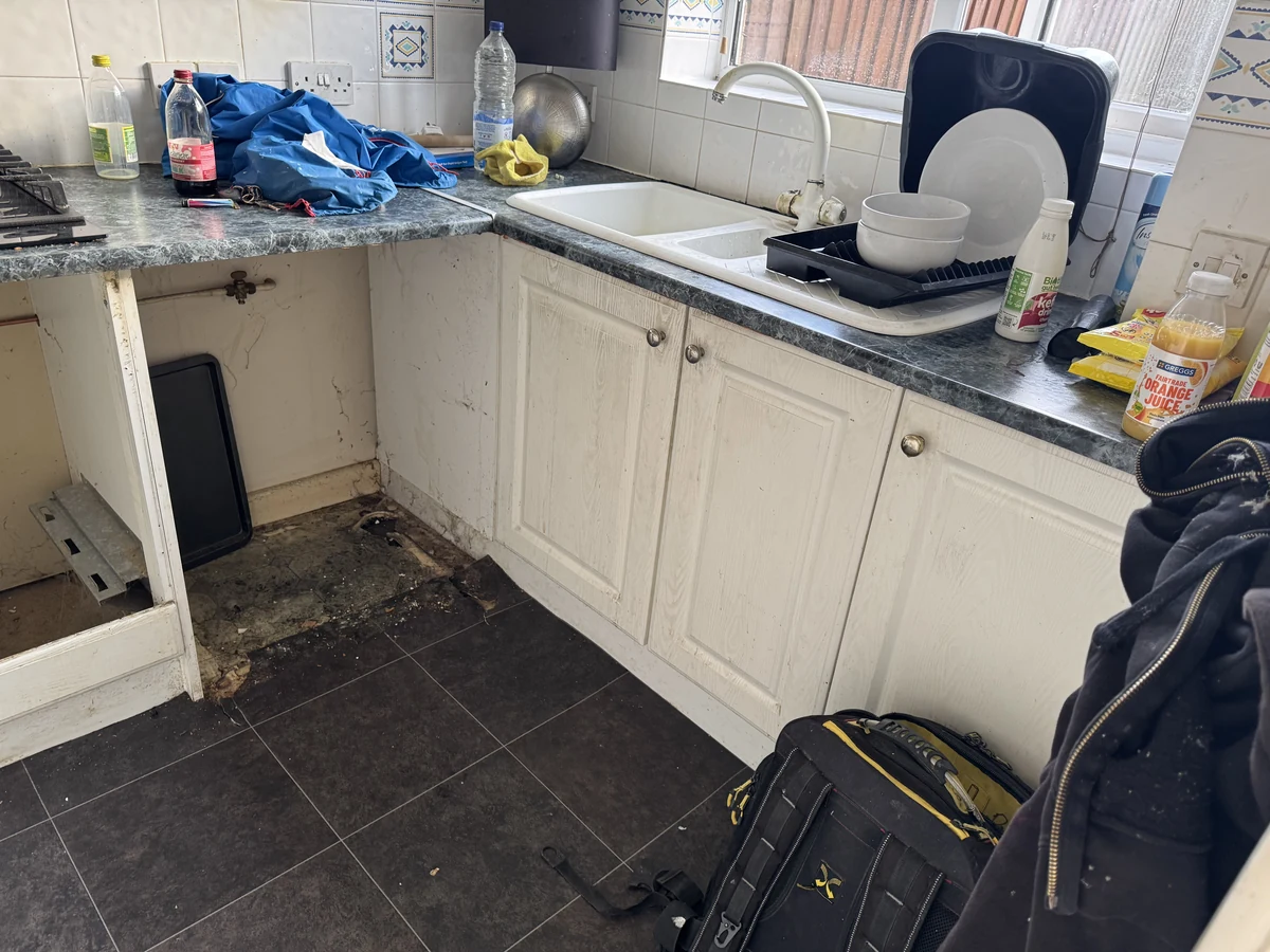 Dated kitchen before refurbishment in Neath, Swansea, with worn base units and old vinyl flooring, by Daffodil Decor