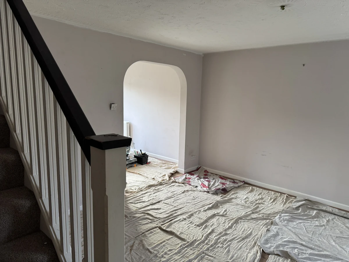 living-room-painting-grey-walls-archway-dust-sheets-swansea-daffodil-decor Room with floor and staircase covered in dust sheets ready for painting