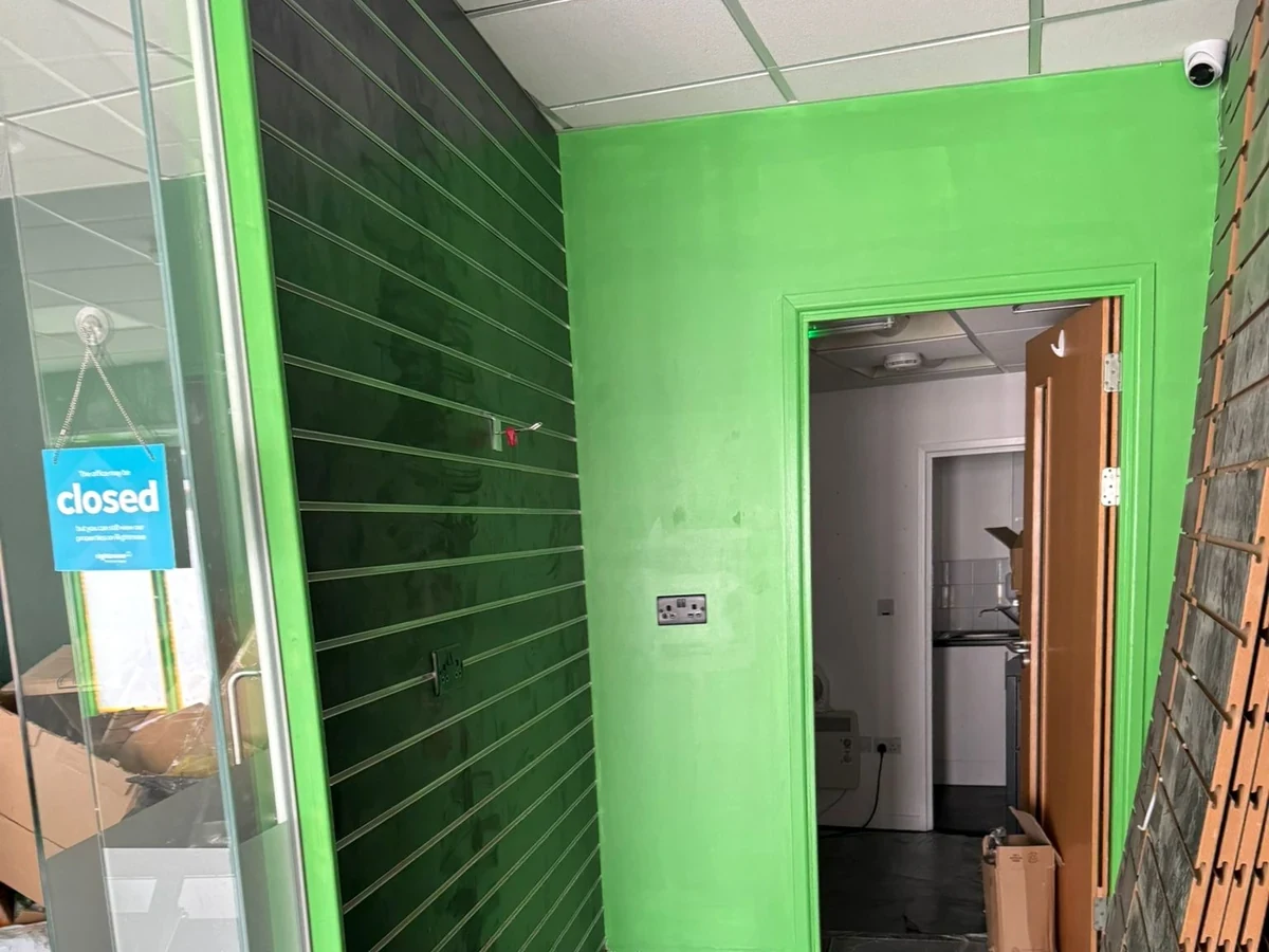 Bright green interior feature wall and product display in the Wimozee Technology shop, Swansea, by Daffodil Decor